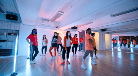 A group of students and the dancing teacher are doing the same dance moves at BFit Dance Studio.