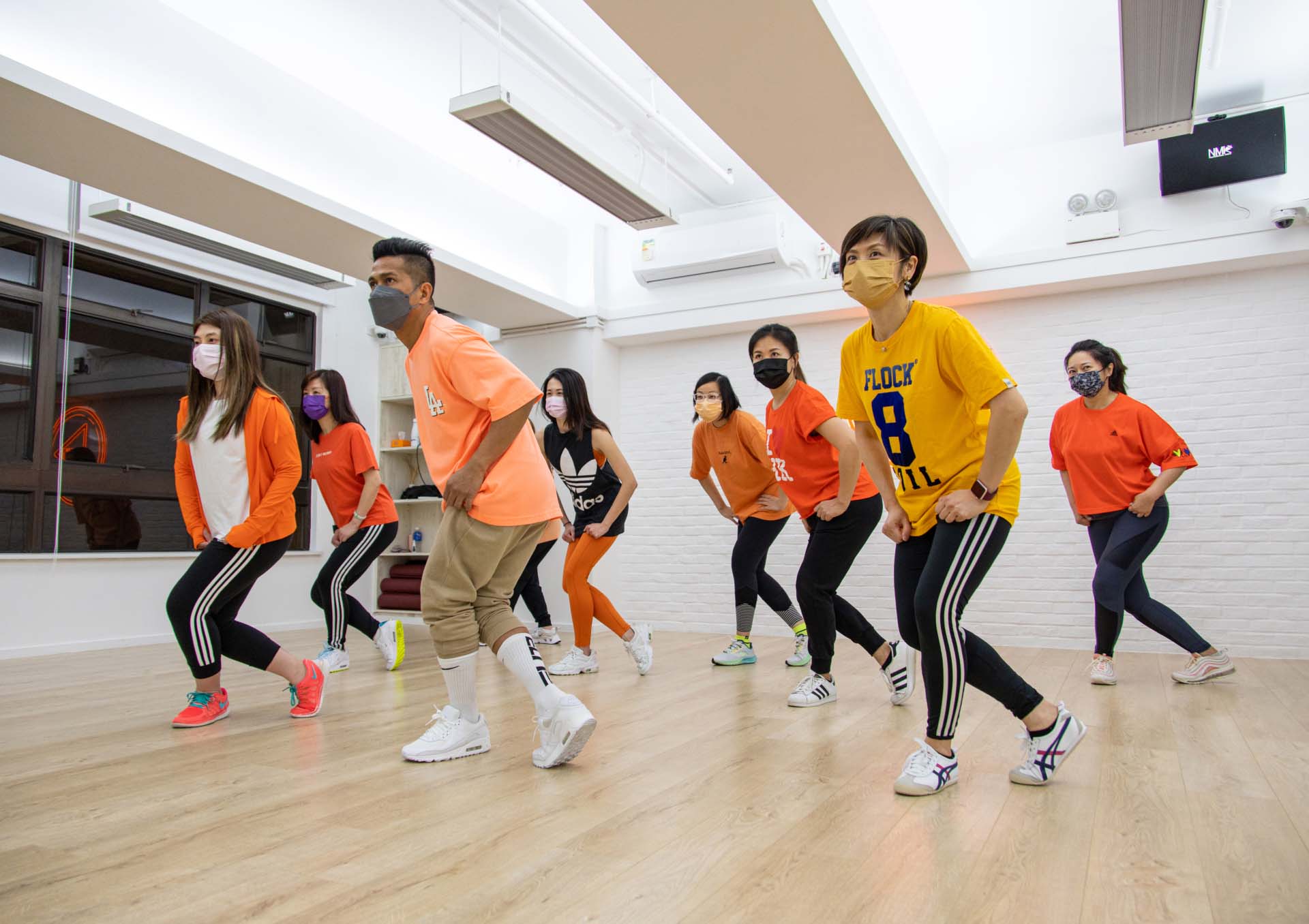 A group of students and the dancing teacher are doing the same dance moves at BFit Dance Studio.